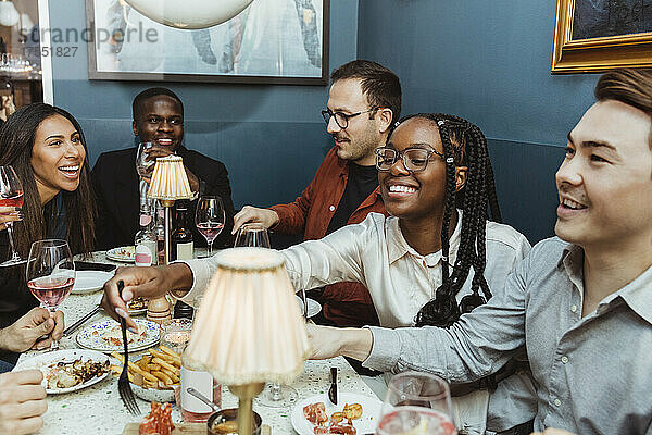 Multirassische weibliche und männliche Freunde beim Essen am Tisch im Restaurant