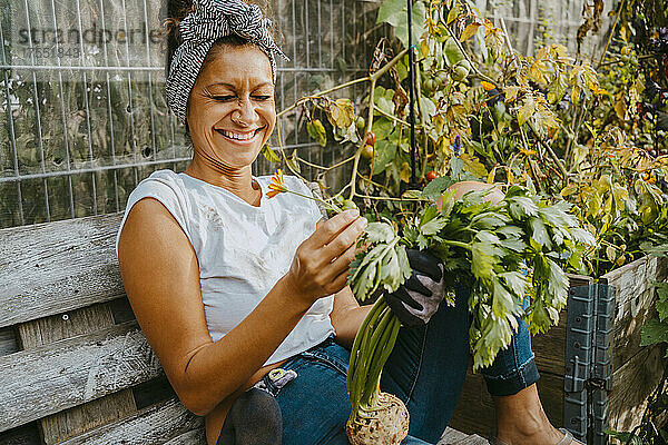 Glückliche Umweltschützerin mit Gemüse auf einem städtischen Bauernhof