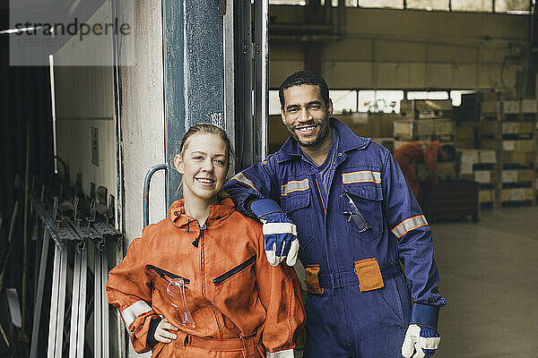 Selbstbewusste männliche und weibliche Arbeiter in Arbeitsschutzkleidung in einer Fabrik
