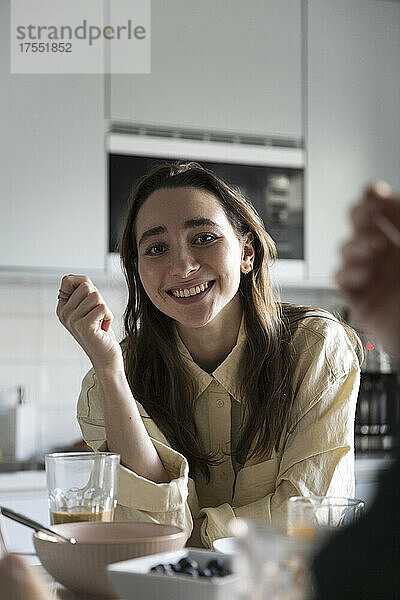 Porträt einer lächelnden Frau beim Frühstück am Tisch