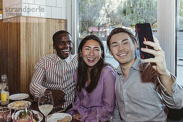 Fröhliche männliche und weibliche Freunde machen ein Selfie mit ihrem Smartphone im Restaurant