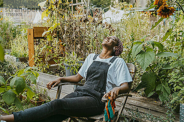 Glückliche landwirtschaftliche Aktionärin entspannt sich auf einem Stuhl im städtischen Garten