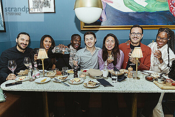Porträt von lächelnden multirassischen Freunden mit Weingläsern in einem Restaurant