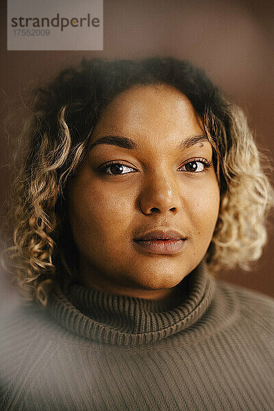 Porträt einer Frau mit Rollkragenpullover vor braunem Hintergrund