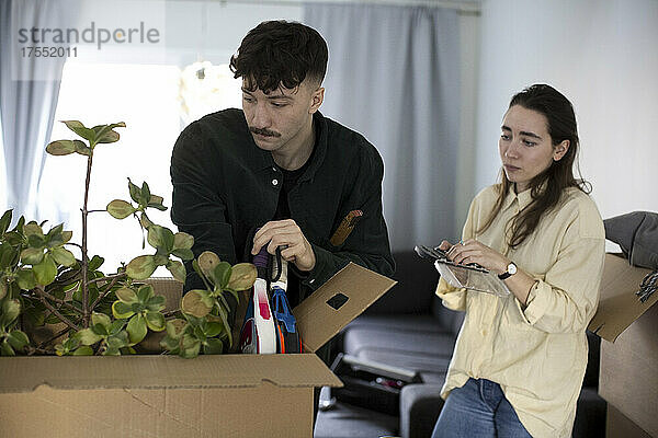 Ein junges Paar betrachtet einen Karton beim Umzug in eine neue Wohnung