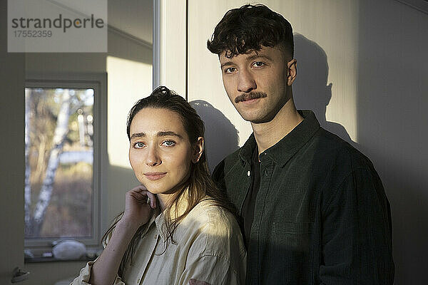 Porträt eines jungen Paares mit Sonnenlicht im Gesicht zu Hause