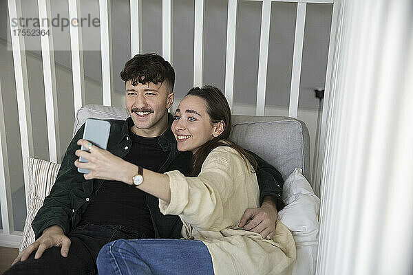 Glückliches junges Paar nimmt Selfie auf Smartphone im Schlafzimmer