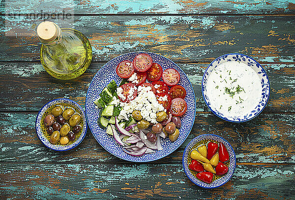 Griechischer Salat mit Tomaten  Feta und Gurke auf Teller dazu verschiedene Vorspeisen
