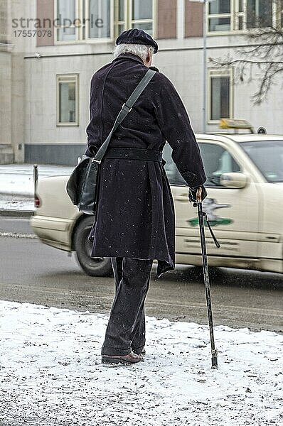 Senior mit Gehstock bei winterlichen Straßenverhältnissen  Berlin  Deutschland  Europa