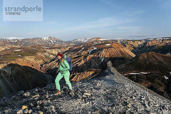 Wanderin auf dem Trekkingweg Laugavegur  Trekkingweg Laugavegur  Dramatische Vulkanlandschaft  bunte Erosionslandschaft mit Bergen  Lavafeld  Landmannalaugar  Fjallabak Naturreservat  Suðurland  Island  Europa