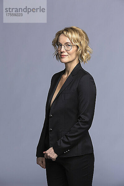 Studio-Porträt selbstbewusste blonde Geschäftsfrau mit Brille im Anzug