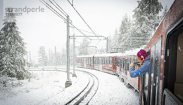 Mann fotografiert den Schneefall auf den Bergen während einer Fahrt mit der Gornergrat Bahn  Zermatt  Wallis  Schweiz  Europa