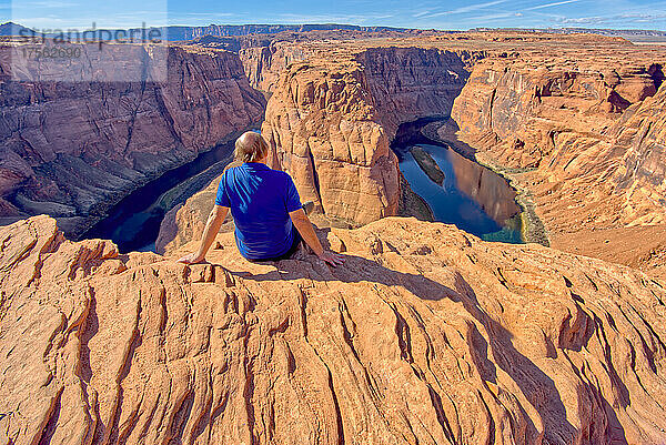Ein Mann sitzt am Rande einer Klippe mit Blick auf Horseshoe Bend in der Nähe von Page  Arizona  Vereinigte Staaten von Amerika  Nordamerika