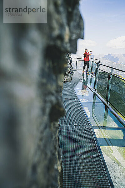 Mann fotografiert Berge mit Smartphone vom Thrill Walk Panorama-Glassteg  Murren Birg  Kanton Bern  Schweiz  Europa