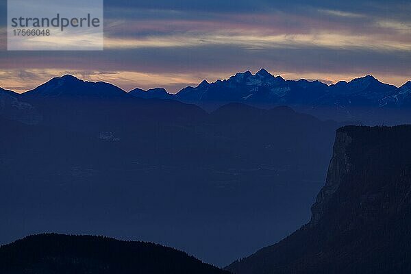 Dramatischer Wolkenhimmel mit Berggipfeln bei blauer Stunde  Zaun mit herbstlichen Lärchen (Larix) und Bergen im Hintergrund  Natruns  Südtirol  Italien  Europa