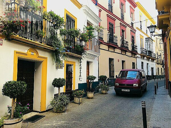 Roter VW Bus auf enger Straße zwischen typischen Häusern in der Altstadt  Sevilla  Andalusien  Spanien  Europa
