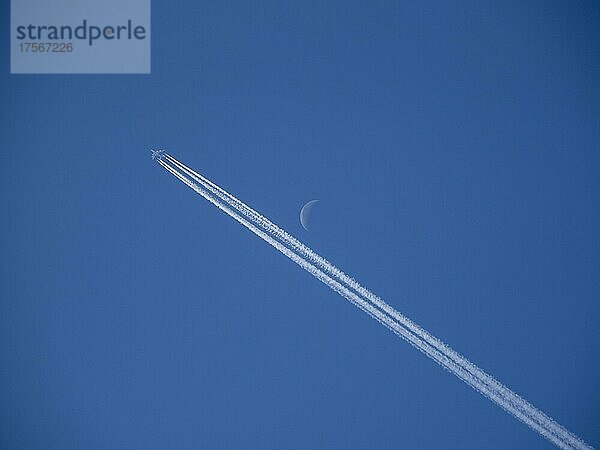 Flugzeug mit Kondensstreifen und Mondsichel