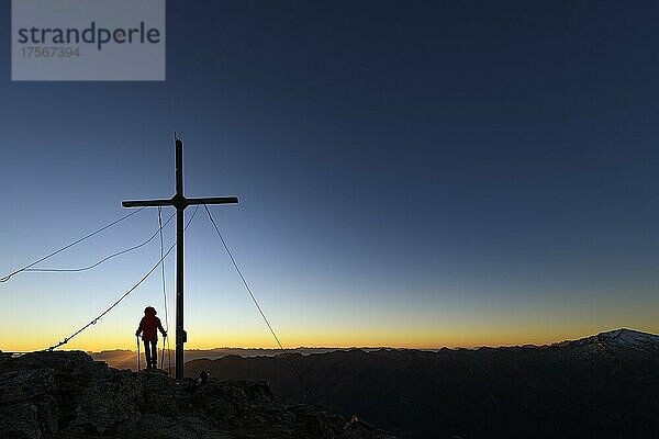 Gipfelkreuz Vermoispitze mit Bergsteiger bei Sonnenaufgang mit Südtiroler Bergen im Hintergrund  Naturns  Südtirol  Italien  Europa