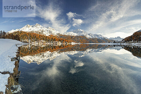 Herbstwälder und schneebedeckte Berge spiegeln sich im klaren Wasser des Champfer Sees bei Sonnenuntergang  Engadin  Graubünden  Schweiz  Europa