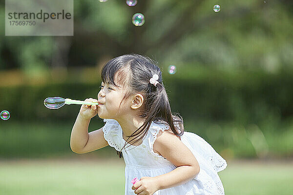 Japanisches Mädchen  das mit Seifenblasen spielt