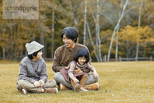 Japanische Familie sitzt auf dem Rasen
