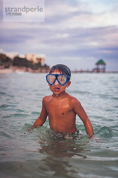 Junge schwimmt mit Schutzbrille im Meer.