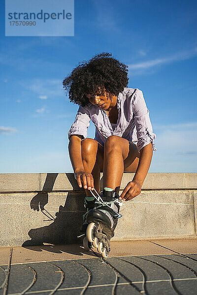 Schöne junge schwarze Frau zieht Inline-Skates an