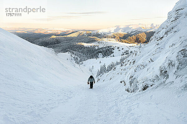 Fotograf wandert bei Sonnenuntergang auf gefrorener Landschaft und hält seine Kamera in der Hand