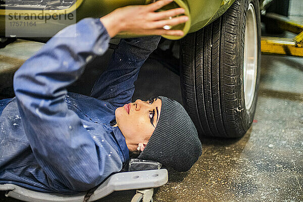 Autoarbeiterin bereitet sich unter dem Auto vor