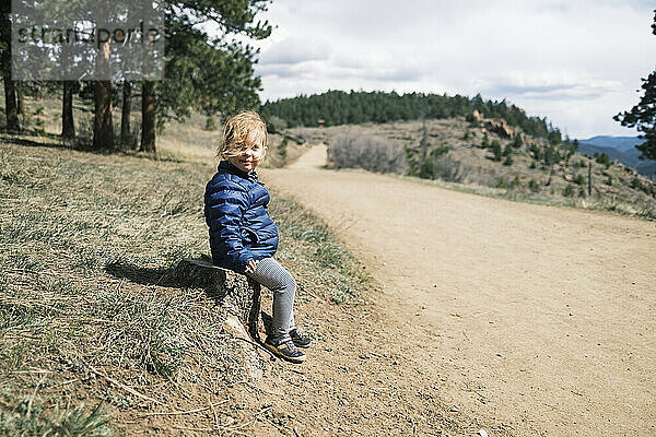 Glückliches Mädchen  das an einem Pfad in Colorado sitzt