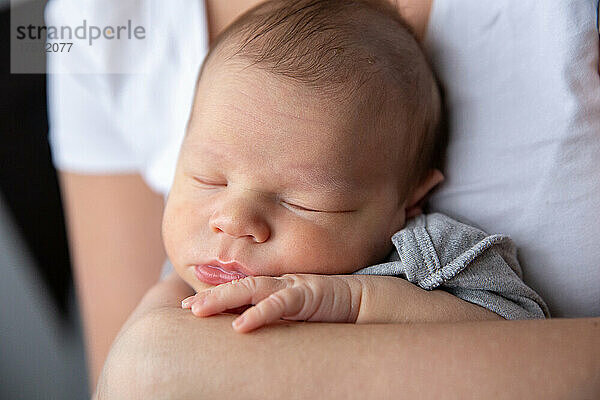 Porträt eines schlafenden Babys in den Armen seiner Mutter