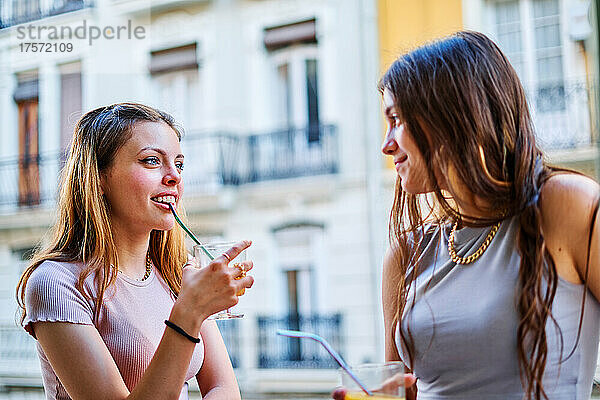 Zwei Freundinnen lachen und trinken auf einer Party im Freien
