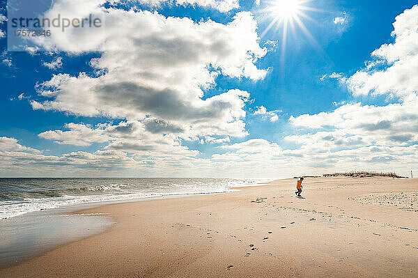 Ein Junge läuft an einem sonnigen Tag am Strand