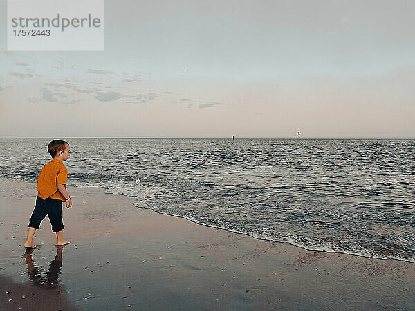 Kleiner Junge blickt am Strand auf das Meer