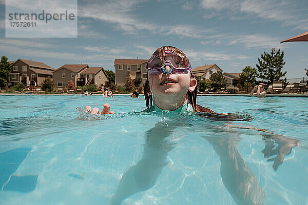 Junges Mädchen schaut an einem sonnigen Tag im Pool nach oben