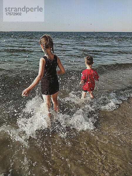 Zwei Kinder vergnügen sich im Plätschern des Meeres am Ufer