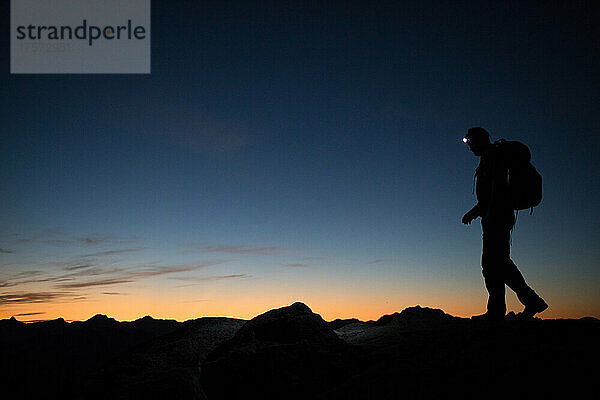 Rucksacktourist navigiert nachts mit einer Heillampe über den Bergrücken.