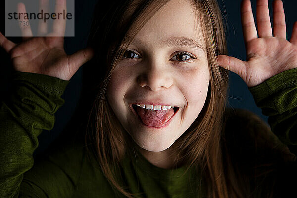 Süßes lächelndes kleines 9-jähriges Mädchen  das ihre Zunge zeigt