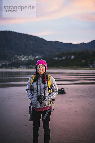 Alleinreisende Frau erkundet einen Strand in Oregon bei Sonnenaufgang