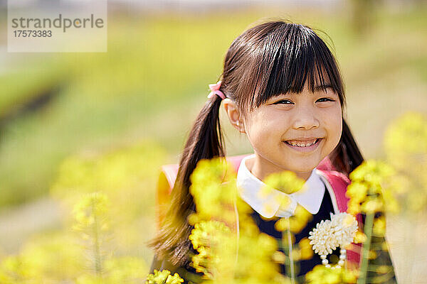 Japanisches Grundschulmädchen lächelt mit Vergewaltigungsblüten
