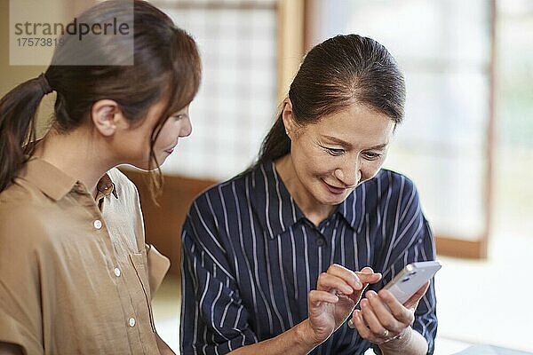Japanische Seniorin  die lernen möchte  wie man ein Smartphone benutzt
