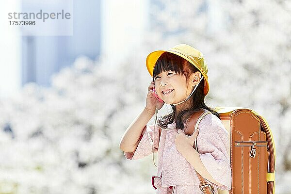 Japanisches Grundschulmädchen  das ein Handy für Kinder bedient