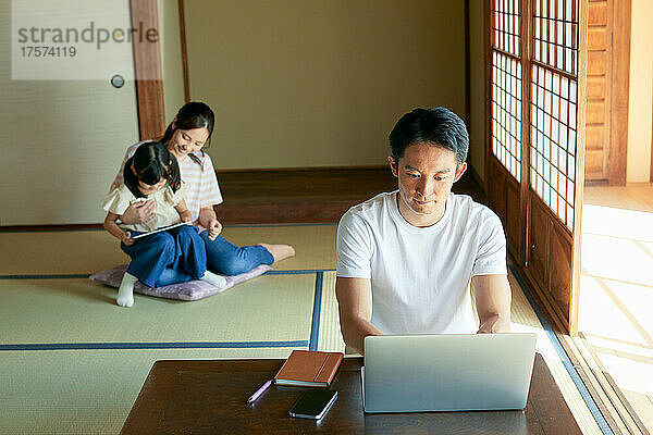 Japanischer Mann  der von zu Hause aus arbeitet  und seine Familie
