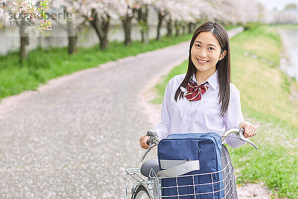 Japanisches Highschool-Mädchen schiebt ihr Fahrrad