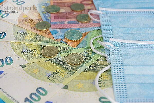 Medizinische Masken und Euro-Banknoten. Finanzkrise aufgrund von Coronavirus Verlusten  selektiver Fokus