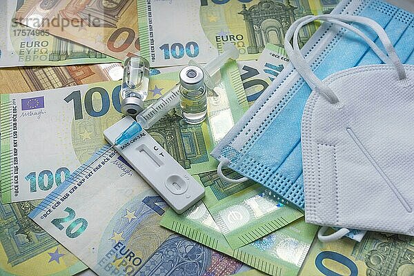 Geld (Euro-Banknoten) mit medizinischer Maske  Antigentest  Impfstoffflaschen und Spritze. Finanzkrise aufgrund von Coronavirus-Verlusten  selektiver Fokus
