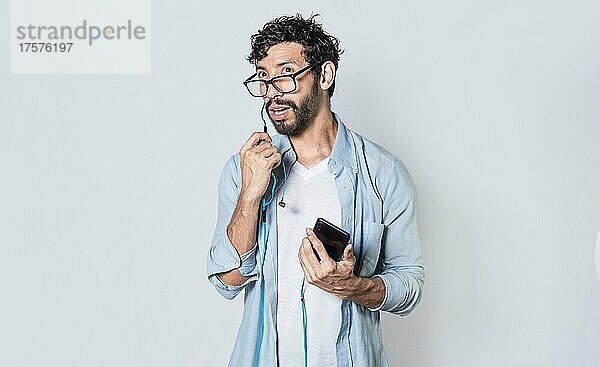 gutaussehender Mann im Gespräch mit Headset und Handy  junger Mann mit Brille und Kopfhörern isoliert