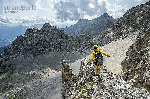 Wanderer balanciert auf Felsvorsprung  Wanderweg zur Lamsenspitze  hinten Kar und felsige Berggipfel mit Mitterkarlspitze  Karwendelgebirge  Alpenpark Karwendel  Tirol  Österreich  Europa