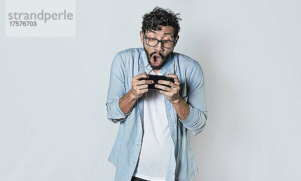 Mann hält Handy horizontal  Kerl keucht und spielt Spiele auf seinem Smartphone