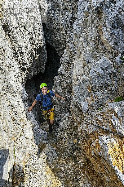 Junger Mann klettert aus einem Felsloch  Klettersteig Brudertunnel  Karwendelgebirge  Alpenpark Karwendel  Tirol  Österreich  Europa